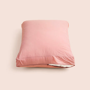 Image of Pink Sandstone Garment Washed Percale Meditation Cushion Cover showcasing a slightly opened zipper with a meditation cushion inside on a light pink background 