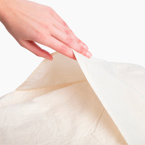 Image of an Ecru Garment Washed Percale Pillow Sham with a hand reaching down to open and showcase the enveloping design on the back