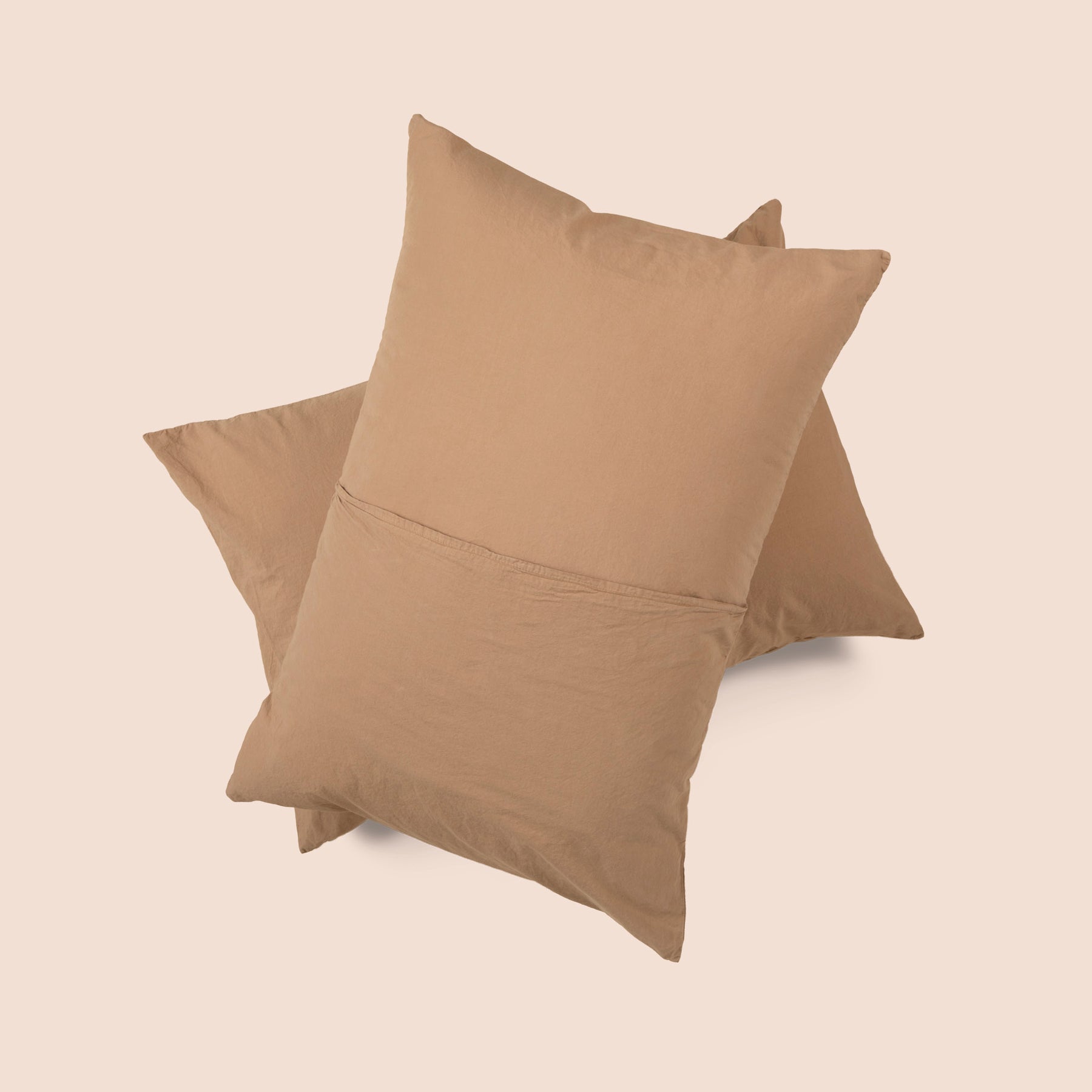 Image of the back of the Ochre Garment Washed Percale Pillow Sham on two pillows stacked on top of one another with a light pink background