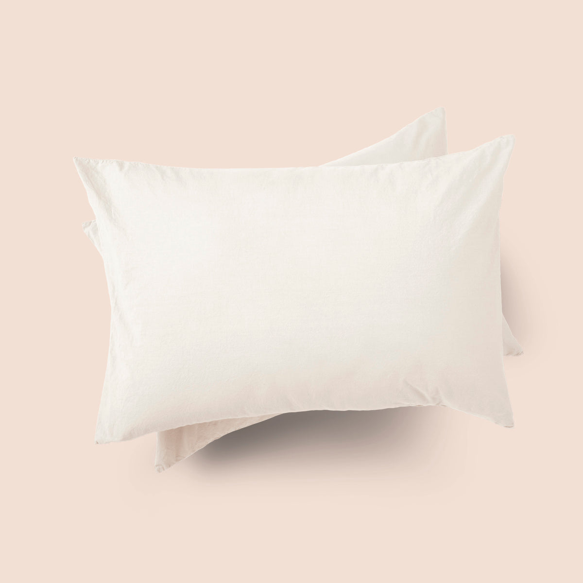 Image of the top of the Ecru Garment Washed Percale Pillow Sham on two pillows stacked on top of one another with a light pink background