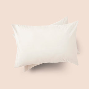 Image of the top of the Ecru Garment Washed Percale Pillow Sham on two pillows stacked on top of one another with a light pink background