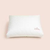 Image of a white, square Meditation Cushion shown from an top-angled view on a light pink background with the Dr. Andrew Weil + Purecare logo sewn on in the bottom right corner