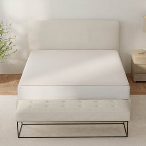 Image of a bed showcasing the Dr. Weil Signature Mattress Protector with brown piping along the edges