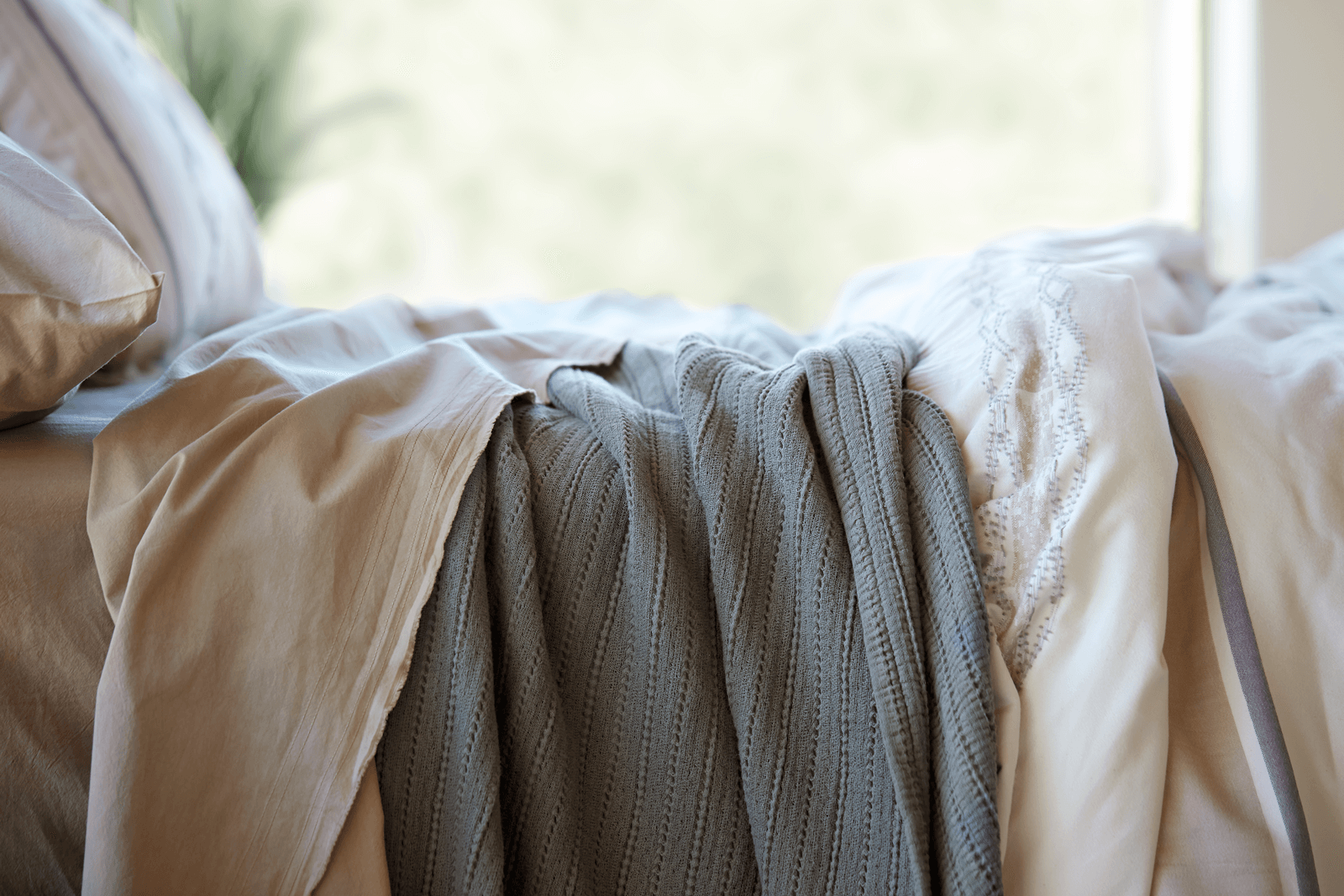 Close-up image of the Sonoran Bundle on a bed including: Ochre Garment Washed Percale Sheets, an Agave Ridgeback Coverlet, and a Sonoran Duvet Cover.