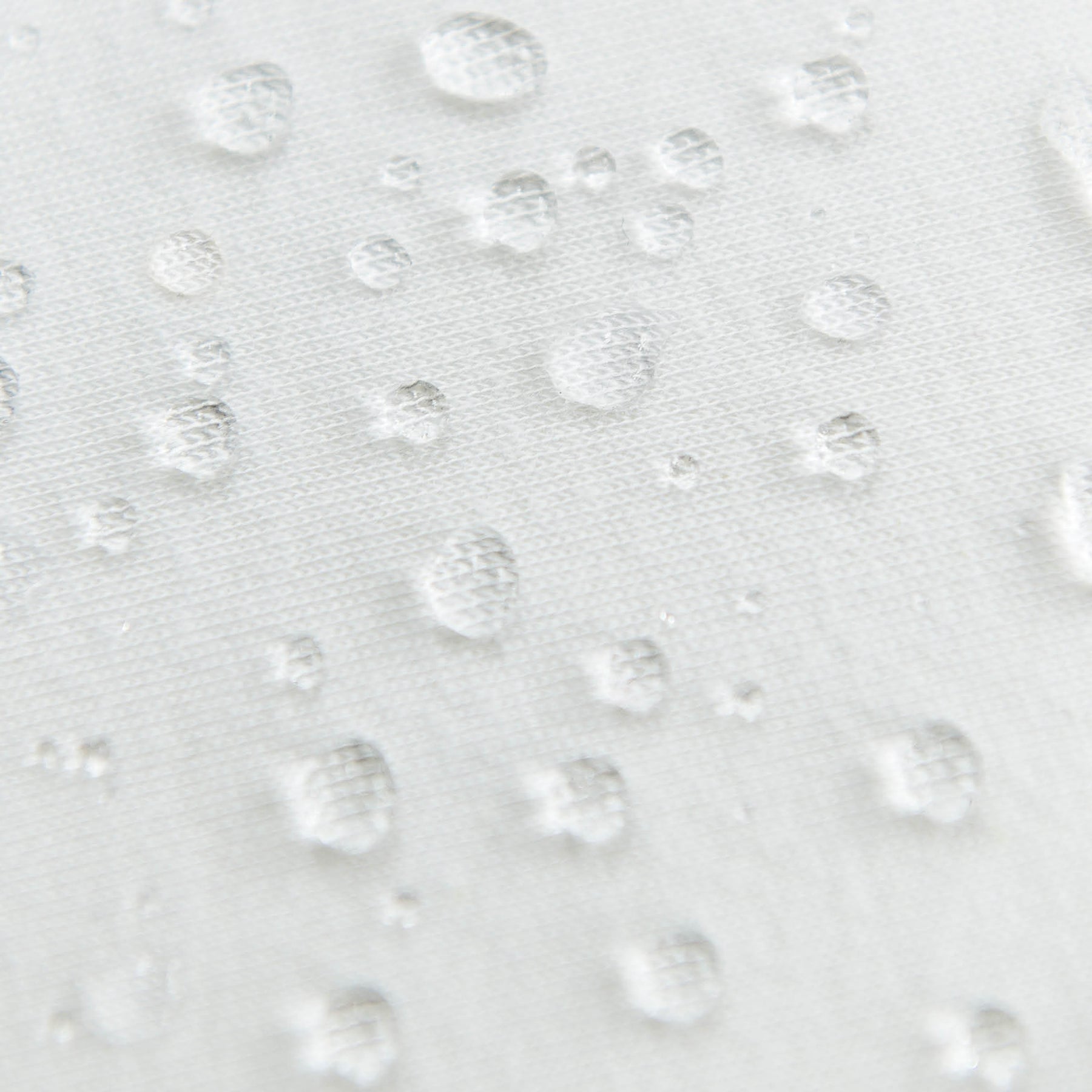 Close-up image of the white mattress protector fabric with water droplets all over
