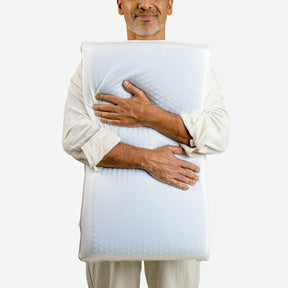 Image of a man smiling and hugging the Cooling Replenish Pillow against his chest with the cool gel side facing forward