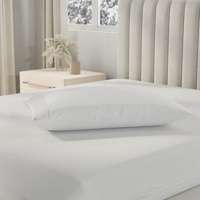 Image of a pillow with a Cooling Pillow Protector on it on top of a bed with just a Total Encasement Mattress Protector