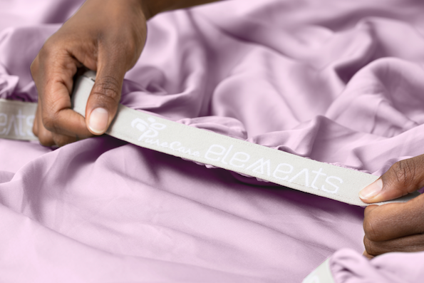 Close-up image of two hands stretching the elastic Precision-Fit® cuff on a Lilac Refreshing TENCEL™ Lyocell fitted sheet