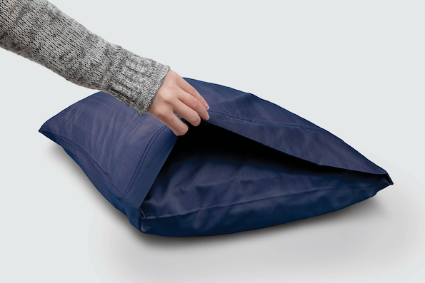 Image of a hand holding open the side of a Midnight Bamboo Pillowcase showcasing the enveloping design
