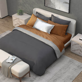 Top-down image of a bedroom with a dressed bed with Clay Recovery Viscose Sheets and a dark gray duvet cover on top