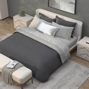 Top-down image of a bedroom with a dressed bed with Dove Gray Recovery Viscose Sheets and a dark gray duvet cover on top