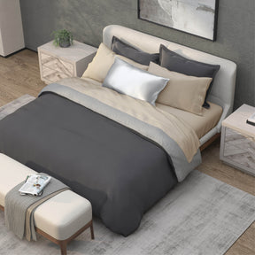 Top-down image of a bedroom with a dressed bed with Ivory Recovery Viscose Sheets and a dark gray duvet cover on top
