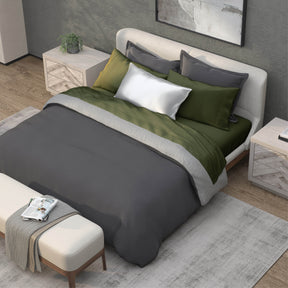 Top-down image of a bedroom with a dressed bed with Moss Recovery Viscose Sheets and a dark gray duvet cover on top