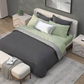 Top-down image of a bedroom with a dressed bed with Sage Recovery Viscose Sheets and a dark gray duvet cover on top