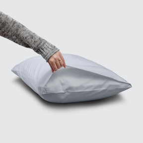 Image of a Light Blue Refreshing TENCEL™ Lyocell Pillowcase on a pillow with a hand lifting up the edge to showcase the enveloping design