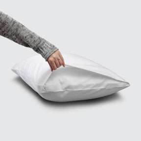 Image of a White Refreshing TENCEL™ Lyocell Pillowcase on a pillow with a hand lifting up the edge to showcase the enveloping design