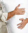 Image of a man hugging a Cooling Shattered Ice Pillow against his chest. The background of the image is a close-up of the snowflake design on the cover of the pillow