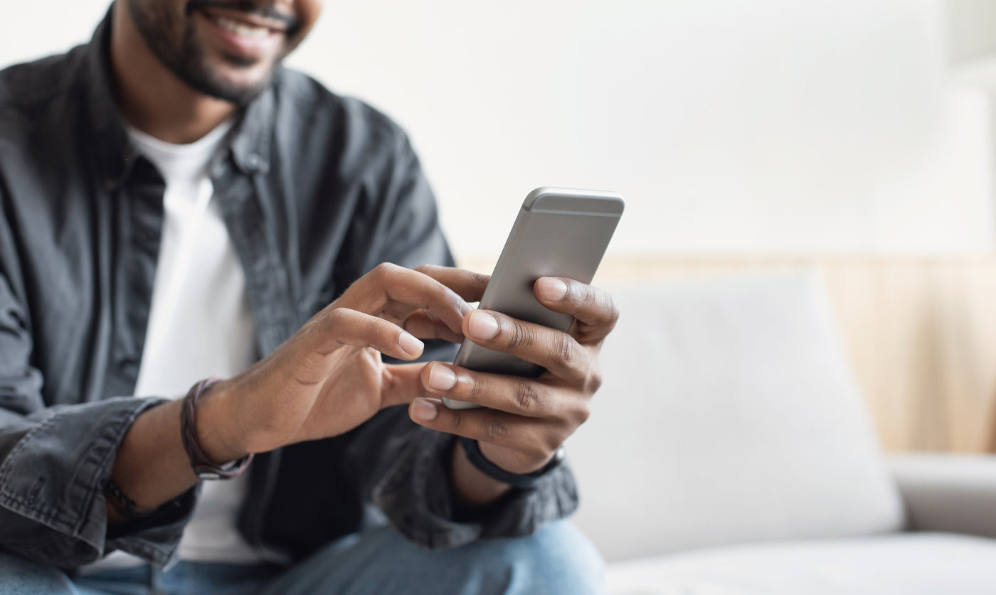 Image of a man sitting on a gray couch holding a phone