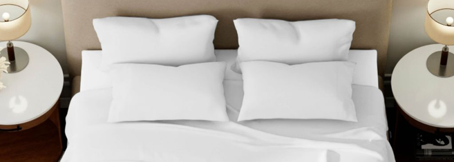 White sheets and four pillows on a tan bed