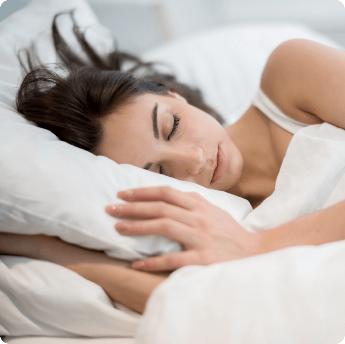 Image of a woman asleep in bed with all-white bedding
