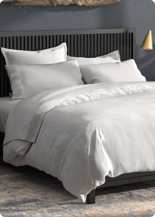 Image of a bed with all-white bedding in a dark colored room
