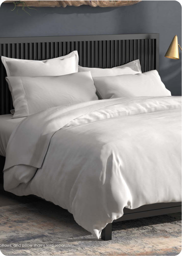 Image of a bed with all-white bedding in a dark colored room