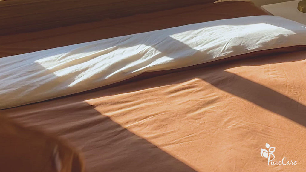 Video of pillows with Ivory/Clay Pillow Shams + Cooling being tossed on a bed, then neatly placed and zipped up