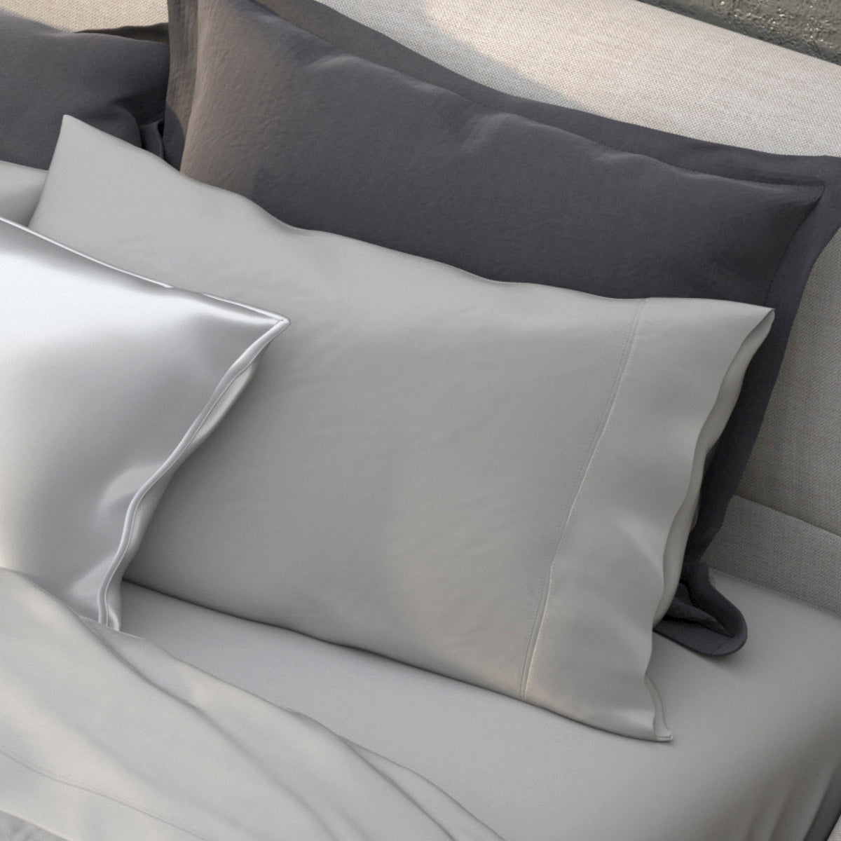 Image of various pillows on a bed in shades of gray with the middle one showcasing the Dove Gray Recovery Viscose Pillowcase