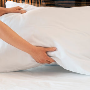 Image of two hands setting down a pillow on a bed