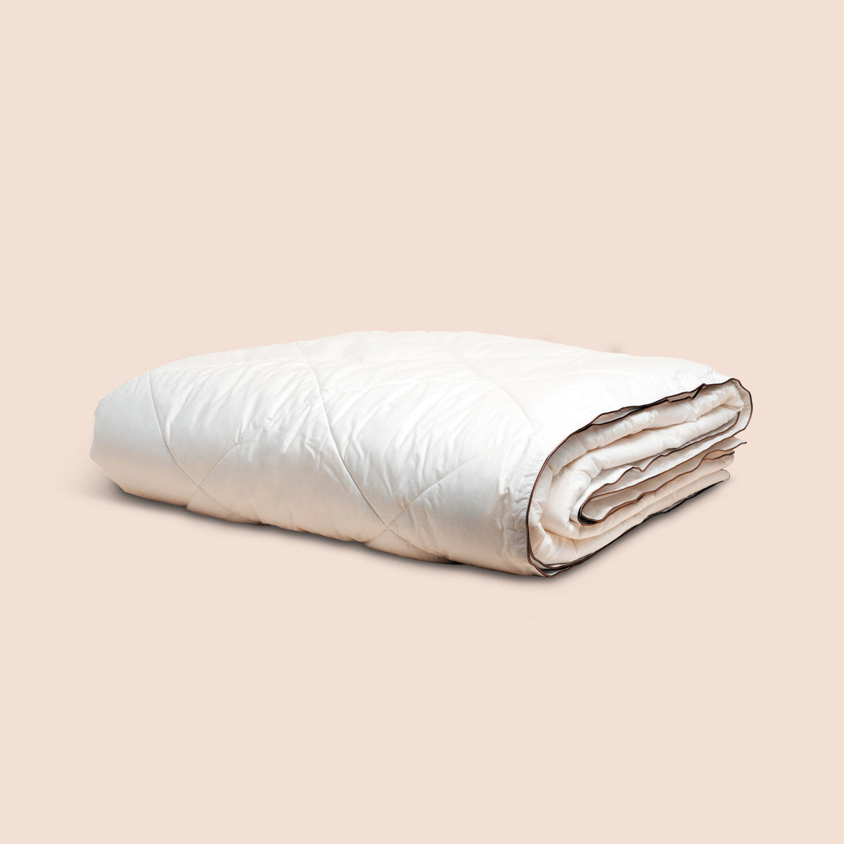 Image of off-white neatly folded duvet insert on light pink background