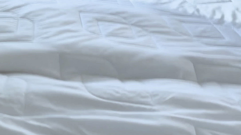 Video of the Duvet Insert + Cooling being laid out on a bed, panning over the insert from various angles. It then shows a woman tying the insert to an Ivory/Clay Duvet Cover and making the bed. 