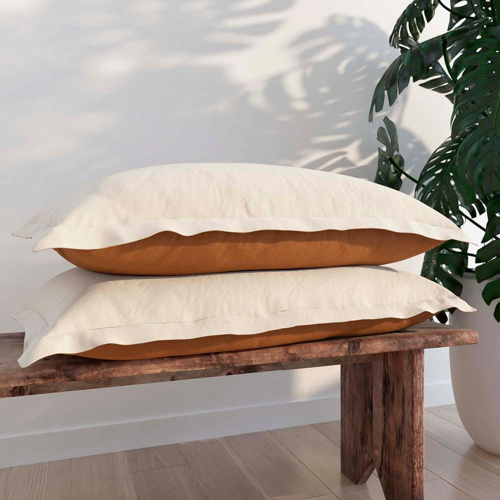 Image of two Ivory/Clay Pillow Shams + Cooling on pillows stacked on a wooden bench